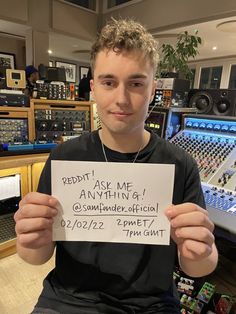 a man holding up a sign in front of sound equipment