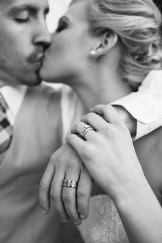 a man and woman kissing each other with their hands on the forehead, wearing wedding rings