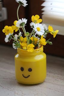 a yellow mason jar with daisies and flowers in it