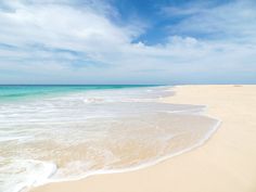 an empty beach with waves coming in to the shore