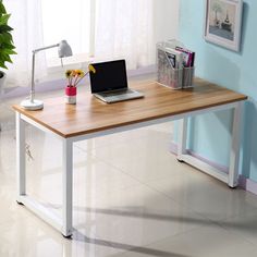 a laptop computer sitting on top of a wooden desk next to a potted plant