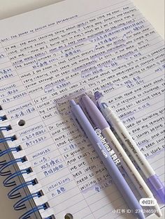 two pens sitting on top of an open notebook