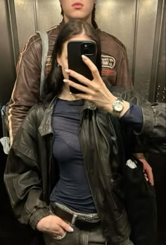 a woman taking a selfie with her cell phone in front of an elevator door