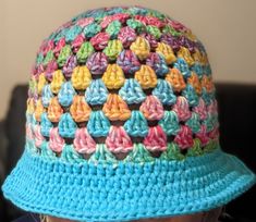 a child wearing a crocheted hat with multicolored yarns on it