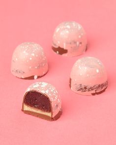 four pieces of cake sitting on top of a pink surface