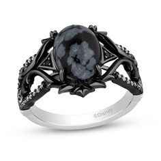 a black and white ring with an oval stone in the center, surrounded by diamonds