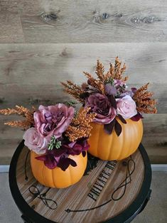 two pumpkins decorated with flowers sitting on a table