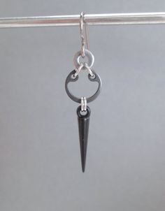 a pair of earrings hanging from a hook on a metal bar with an arrow charm attached to it