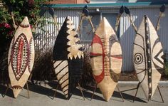 five surfboards are lined up in front of a fence and some bushes on the sidewalk