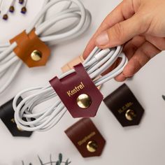 a person is holding a red and white cord in front of several leather tags on the table