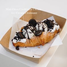 an ice cream croissant with oreo cookies on top in a cardboard box