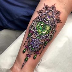 a woman's leg with a green and purple tattoo design on the side of her arm