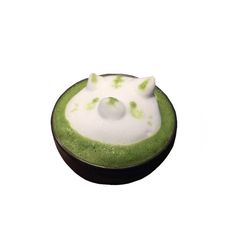 a green cupcake with white frosting and sprinkles in the shape of a cat