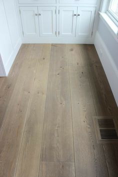 a wood floor in a kitchen with white cabinets