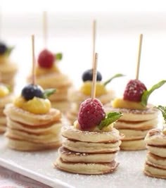 small pancakes with fruit on top and toothpicks sticking out of the stacks are ready to be eaten