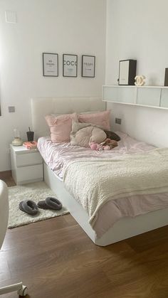 a bedroom with white walls and wooden flooring has a pink bed spread on it