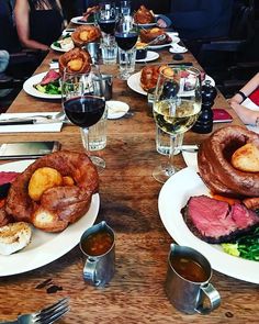 a table with several plates of food and glasses of wine