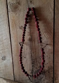 a red beaded necklace hanging on a wooden wall