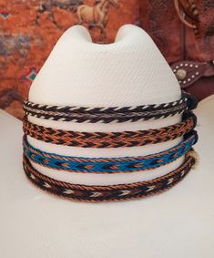 Braided Horse Hair Adjustable Hat Band in Brown/Black, Turquoise/Brown/Black, or Black/Brown/White, with 2 sliding knots make this hatband a great fit for most hats. This stunning hat band is made from genuine braided horse hair and will compliment your favorite cowboy hat.   - 3 braided strands are sewn together to create this gorgeous hatband. - Hat band measurements: approximately adjusts to 27.5" around and is 3/8 inch wide - Hat bands are shown on a size 7 hat.  Hats are not included. - See my horse hair KEEPSAKES to have a hat band made from your horse's hair:  https://www.etsy.com/shop/BlueEyesDesignsHB?ref=seller-platform-mcnav§ion_id=43697745 - See my HORSE HAIR hat bands:  https://www.etsy.com/shop/BlueEyesDesignsHB?ref=shop-header-name&listing_id=1296906619&from_page=listing&sec Adjustable Beach Hat Bands, Adjustable Multicolor Headband For Beach, Adjustable Blue Hat Bands For Vacation, Adjustable Woven Blue Hats, Adjustable Blue Woven Hats, Blue Adjustable Woven Hats, Horse Hair Hat Band, Cowboy Hat Bands, Hair Keepsake