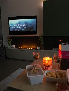 two glasses of wine are sitting on a table with food in front of the tv