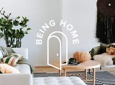 a living room filled with furniture and a large white sign over the door that says being home