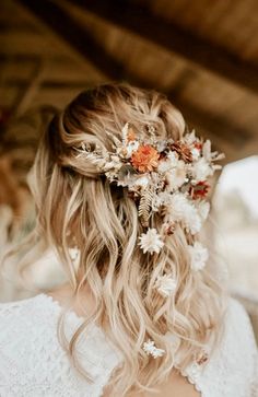 a woman with flowers in her hair wearing a white dress and holding a flower crown