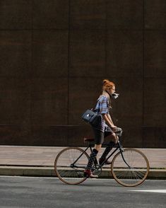 a woman with red hair riding a bike down the street