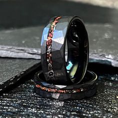 two wedding bands with different designs on them sitting next to each other in front of a black surface