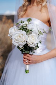 a bride holding a bouquet of white roses