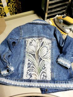 an old jean jacket with embroidered flowers on it