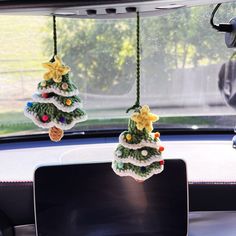 two christmas trees hanging from the dash board of a car, decorated with crochet