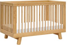 a small wooden crib with white sheets on the bottom and sides, against a white background