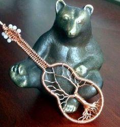 a bear figurine sitting on top of a wooden table holding a guitar string