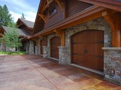 a large house with two garages in front of it and stone pillars on the side