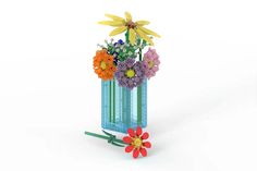 a vase filled with colorful flowers on top of a white table next to a green stick