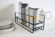 there are many cups and plates on the counter together in this kitchen holder, which is also holding two coffee mugs