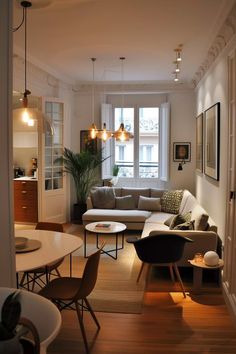 a living room filled with furniture next to a window covered in light fixture shades and hanging lights