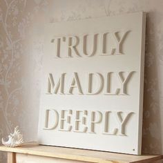 there is a sign that says truly madly deeply on the wall next to a shelf