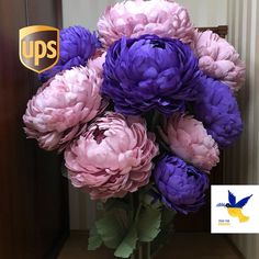 a vase filled with purple and pink flowers on top of a wooden floor next to a doorway