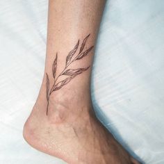 a small tattoo on the foot of a woman's left leg, with leaves