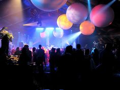 a large group of people at a party with balloons in the air and onlookers