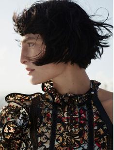 a woman with black hair wearing a floral top