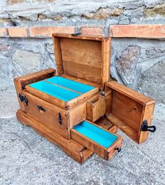 an open wooden box sitting on top of a cement floor next to a stone wall