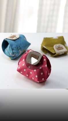 three small fabric pouches sitting on top of a white table next to each other