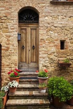 an old stone building with potted plants and flowers on the steps leading up to it