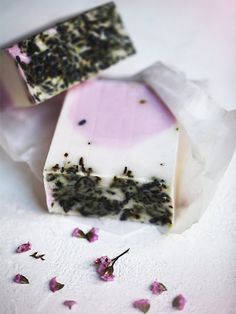 two pieces of soap sitting on top of tissue paper next to pink and white flowers