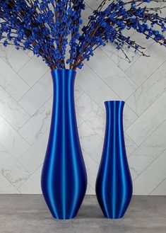 two blue vases sitting on top of a table next to each other with flowers in them