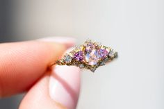 a woman's hand holding a ring with three different colored stones