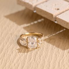 three stone ring sitting on top of a piece of paper next to a white object