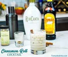 an assortment of liquor bottles and glasses sitting on a counter with cinnamon roll in the foreground